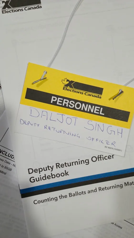 An Elections Canada personnel badge with DALJOT SINGH, DEPUTY RETURNING OFFICER handwritten on it, resting on a Deputy Returning Officer guidebook.